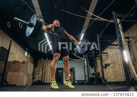 The training process. Athletic man performing weightlifting exercises with a barbell in a gym 137814823
