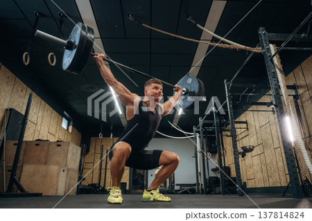 The training process. Athletic man performing weightlifting exercises with a barbell in a gym 137814824