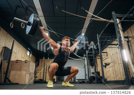 The training process. Athletic man performing weightlifting exercises with a barbell in a gym 137814826