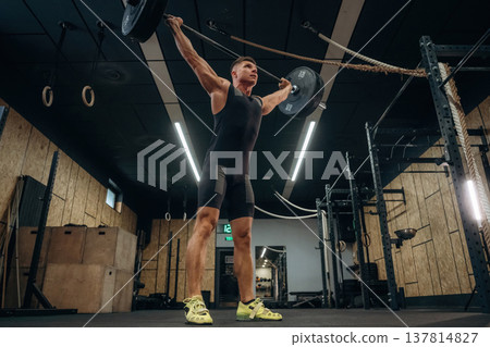 The training process. Athletic man performing weightlifting exercises with a barbell in a gym 137814827