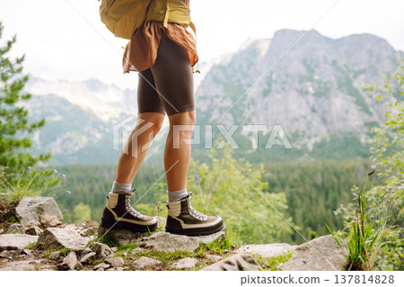 Close-up of female legs in hiking boots on a hiking trail. Travel, vacation. The concept of nature. Close-up of female legs in hiking boots on a hiking trail. Travel, vacation. The concept of nature. 137814828
