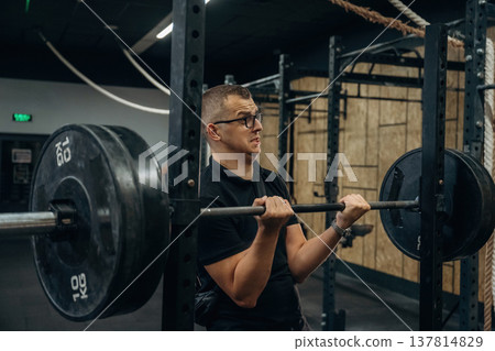 Funny man in glasses is trying to lift the heavy barbell in the gym Funny man in glasses is trying to lift the heavy barbell in the gym 137814829
