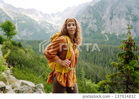 Young traveler woman with a yellow backpack on a cliff. Sports concept, traveler. Active lifestyle. Young traveler woman with a yellow backpack on a cliff. Sports concept, traveler. Active lifestyle. 137814832