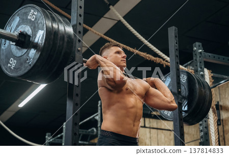 The training process. Athletic man performing weightlifting exercises with a barbell in a gym 137814833
