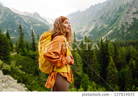 Young traveler woman with a yellow backpack on a cliff. Sports concept, traveler. Active lifestyle. 137814835