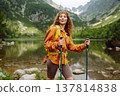 Travel Slovakia, Europe. Tourist with a yellow backpack stands against the backdrop of alpine lake. 137814838