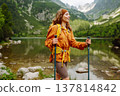Travel Slovakia, Europe. Tourist with a yellow backpack stands against the backdrop of alpine lake. 137814842
