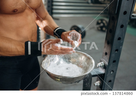 Fitness man is rubbing his hands with chalk, specifically magnesium carbonate Fitness man is rubbing his hands with chalk, specifically magnesium carbonate 137814860