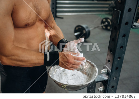 Preparing for competition. Fitness man is rubbing his hands with chalk, specifically magnesium carbonate Preparing for competition. Fitness man is rubbing his hands with chalk, specifically magnesium carbonate 137814862
