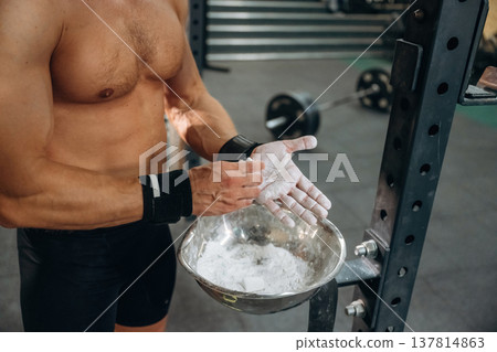 Preparing for competition. Fitness man is rubbing his hands with chalk, specifically magnesium carbonate Preparing for competition. Fitness man is rubbing his hands with chalk, specifically magnesium carbonate 137814863