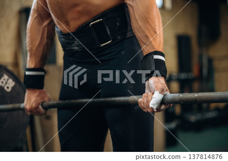Focused on hands. Close up view of athletic man that is lifting heavy barbell 137814876