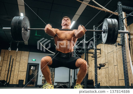 Lifting heavy barbell. Athletic man is in a gym Lifting heavy barbell. Athletic man is in a gym 137814886