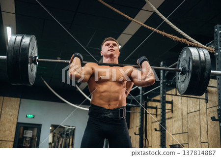 Lifting heavy barbell. Athletic man is in a gym Lifting heavy barbell. Athletic man is in a gym 137814887