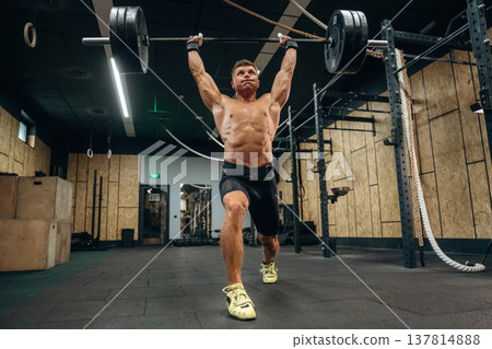 Workout session. Athletic man performing weightlifting exercises with a barbell in a gym Workout session. Athletic man performing weightlifting exercises with a barbell in a gym 137814888