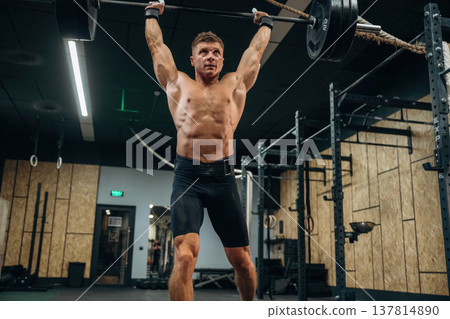 Made it, heavy barbell is high up in the hands. Athletic man performing weightlifting exercises 137814890