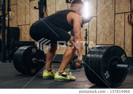 Preparing to do this. Athletic man performing weightlifting exercises with a barbell in a gym Preparing to do this. Athletic man performing weightlifting exercises with a barbell in a gym 137814968