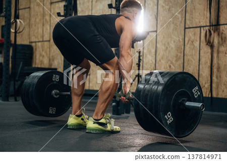 Preparing to do this. Athletic man performing weightlifting exercises with a barbell in a gym Preparing to do this. Athletic man performing weightlifting exercises with a barbell in a gym 137814971
