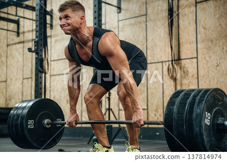 Preparing to do this. Athletic man performing weightlifting exercises with a barbell in a gym Preparing to do this. Athletic man performing weightlifting exercises with a barbell in a gym 137814974