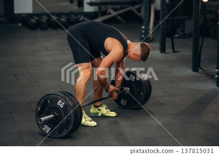 Getting ready. Athletic man performing weightlifting exercises with a barbell in a gym Getting ready. Athletic man performing weightlifting exercises with a barbell in a gym 137815031