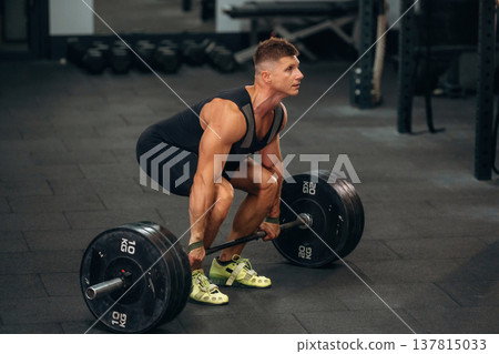 Getting ready. Athletic man performing weightlifting exercises with a barbell in a gym Getting ready. Athletic man performing weightlifting exercises with a barbell in a gym 137815033