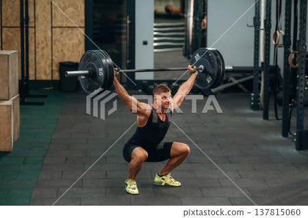 Training process, session. Athletic man performing weightlifting exercises with a barbell in a gym 137815060