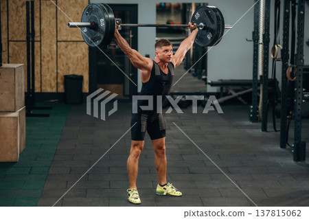Training process, session. Athletic man performing weightlifting exercises with a barbell in a gym Training process, session. Athletic man performing weightlifting exercises with a barbell in a gym 137815062
