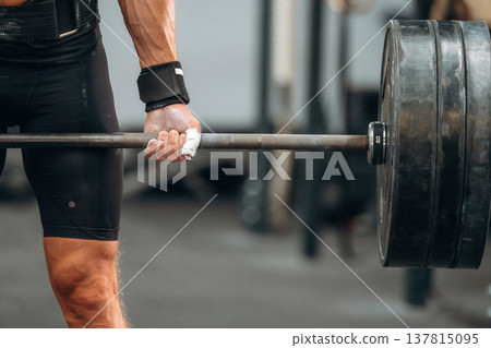Hands are in white powder. Close up view of athletic man that is lifting heavy barbell Hands are in white powder. Close up view of athletic man that is lifting heavy barbell 137815095