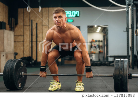 Using quality equipment. Athletic man performing weightlifting exercises with a barbell in a gym Using quality equipment. Athletic man performing weightlifting exercises with a barbell in a gym 137815098