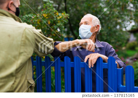 Senior man in mask having conversation with his neighbour 137815165