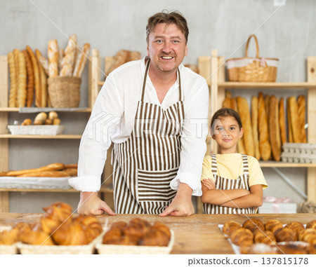 Baker dad and daughter are standing near product range in bakery kitchen. Baker dad and daughter are standing near product range in bakery kitchen. 137815178