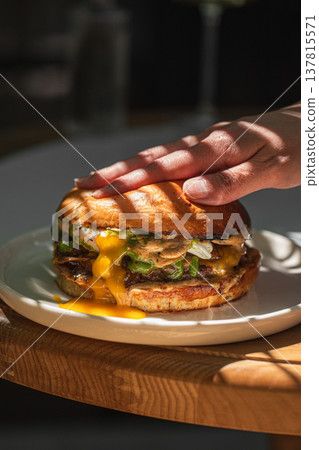 Juicy cheeseburger pressed by hand close up 137815571