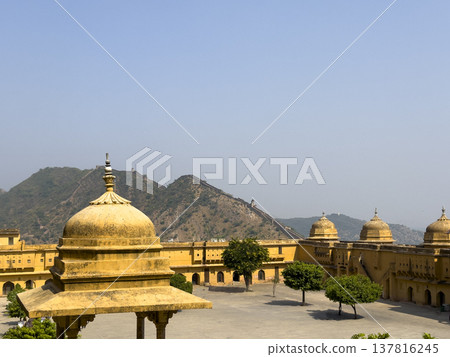 Jaipur fort courtyard features yellow sandstone dome and palace architecture under clear sky. Jaipur fort courtyard features yellow sandstone dome and palace architecture under clear sky. 137816245