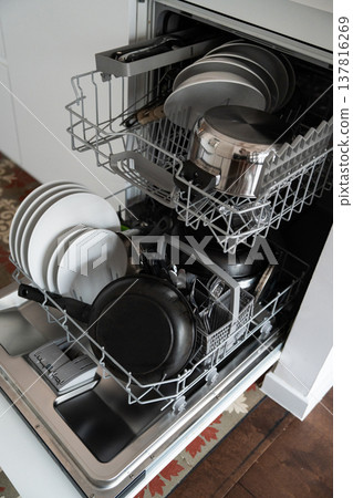Open dishwasher loaded with dirty dishes, plates, bowls, and cutlery, ready for washing, showing the domestic task of everyday kitchen cleaning Open dishwasher loaded with dirty dishes, plates, bowls, and cutlery, ready for washing, showing the domestic task of everyday kitchen cleaning 137816269