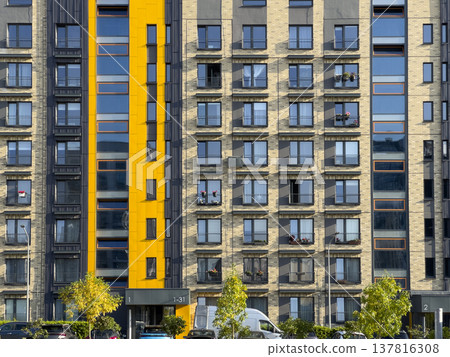Modern apartment building facade in urban residential area. Condominium exterior with yellow Modern apartment building facade in urban residential area. Condominium exterior with yellow 137816308