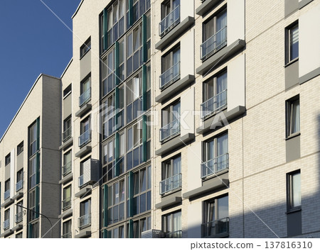 Modern apartment building facade in urban residential area. White brick exterior with glass windows Modern apartment building facade in urban residential area. White brick exterior with glass windows 137816310