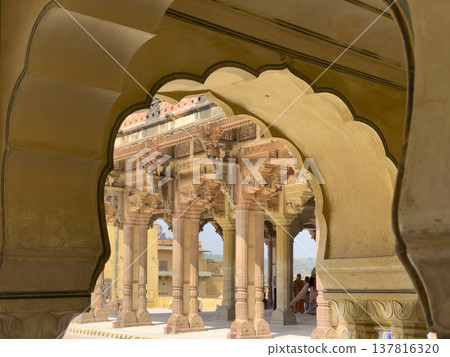 Ornate sandstone arch frames palace courtyard with carved column and decorative facade in Jaipur. Ornate sandstone arch frames palace courtyard with carved column and decorative facade in Jaipur. 137816320