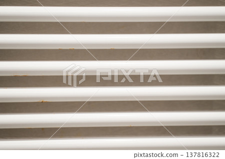 White metal radiator bars with rust spots creating a grunge background texture, showing wear and tear, heating system detail White metal radiator bars with rust spots creating a grunge background texture, showing wear and tear, heating system detail 137816322