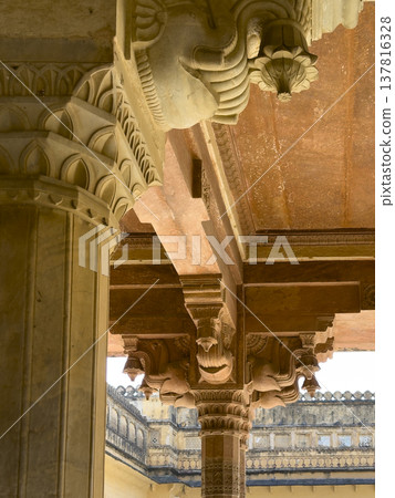 Ornate sandstone column with intricate carving supports palace ceiling in Jaipur architecture. 137816328