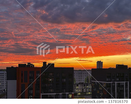 Urban skyline with residential buildings under dramatic red sunset sky. City architecture silhouetted against glowing evening clouds above horizon. Travel destination, metropolitan lifestyle 137816370