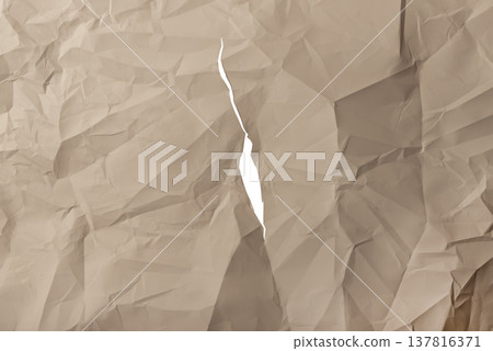 Vertical ripped brown kraft paper shows narrow torn split through crumpled textured surface. Jagged 137816371