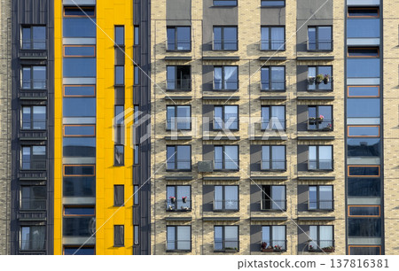 apartment building facade in urban residential area. Brick exterior with yellow accent, geometric 137816381