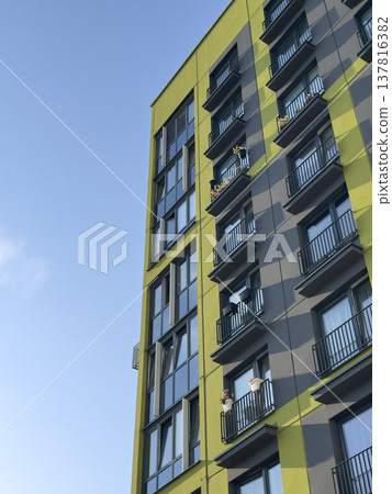 apartment building facade in urban residential area. Green and gray exterior with glass windows and 137816382