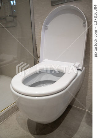 Wall-mounted toilet with open seat, providing modern hygiene and comfort in a minimalist bathroom design, reflecting contemporary home interior and plumbing solutions 137816394