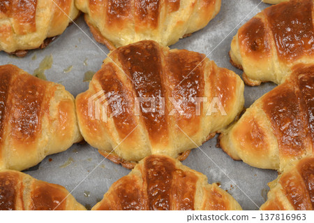 Close up of fresh golden brown croissants on baking paper 137816963