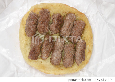 Grilled cevapi meat rolls served on an open lepinja flatbread Grilled cevapi meat rolls served on an open lepinja flatbread 137817002
