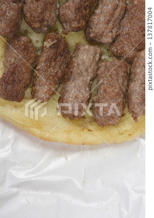Grilled cevapi meat rolls on lepinja bread close up Grilled cevapi meat rolls on lepinja bread close up 137817004