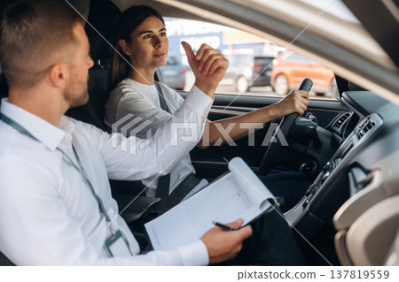 Data is being written into the notepad. Woman is with instructor in car, driving school concept 137819559