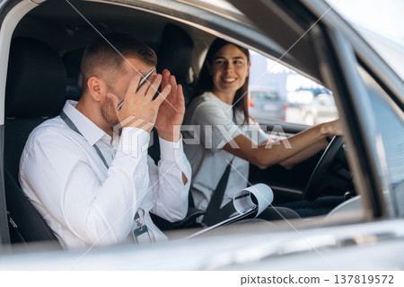 Man is mad, disappointed. Woman is with instructor in car, driving school concept Man is mad, disappointed. Woman is with instructor in car, driving school concept 137819572