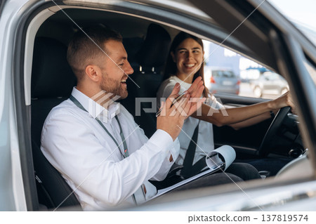 Positive mood, smiling. Woman is with instructor in car, driving school concept 137819574