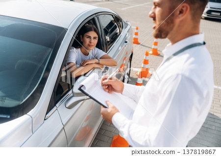 Writing results into notepad. Woman is trying to pass exam in the driving school Writing results into notepad. Woman is trying to pass exam in the driving school 137819867